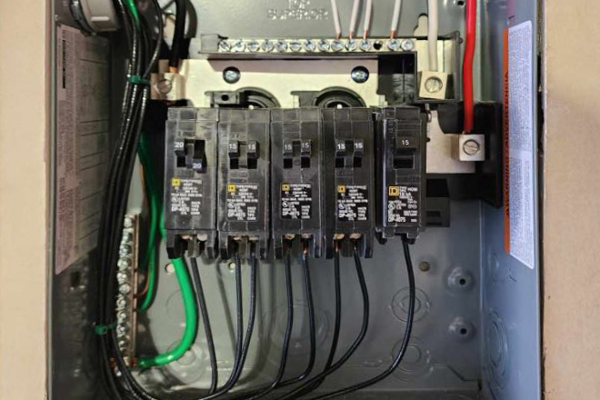 A close-up view of an electrical circuit breaker panel with multiple breakers and connected wiring.