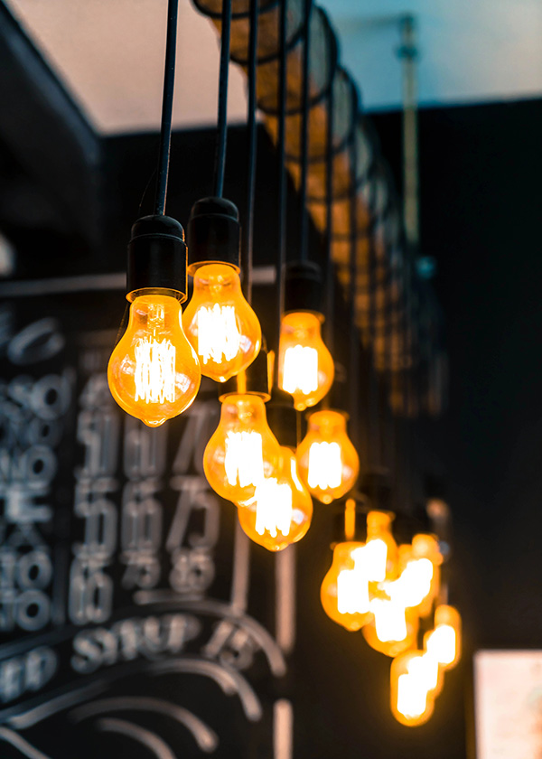 A series of vintage-style Edison light bulbs hang from the ceiling in a dimly lit room, casting a warm glow.